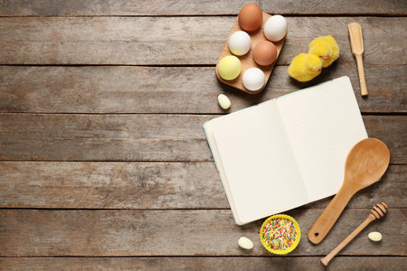 Composition with blank notebook for recipes, Easter eggs and baking tools on wooden backgroundの写真素材