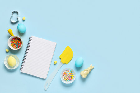 Composition with blank notebook for recipes, Easter eggs, colorful sprinkles and baking tools on color backgroundの写真素材