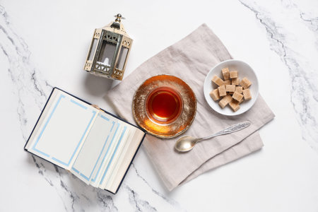Glass of tasty Turkish tea with fanoos and sugar on white marble background. Ramadan celebration