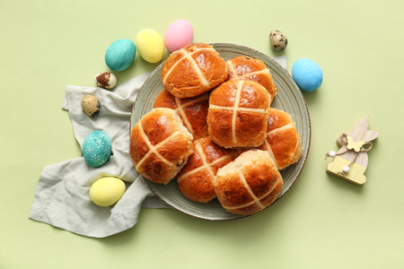 Plate with Easter buns, eggs and napkin on green backgroundの写真素材