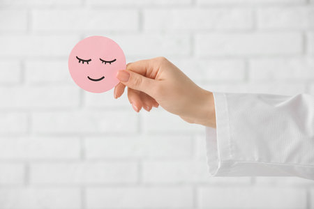 Doctor's hand with paper smile on white brick background. World Health Dayの写真素材
