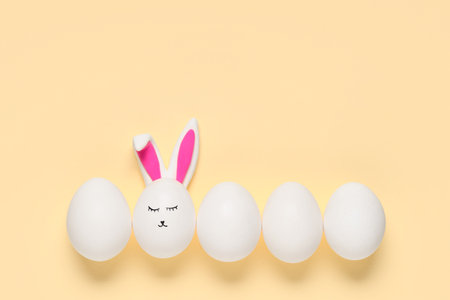 Easter eggs with drawn face and bunny ears on beige backgroundの写真素材