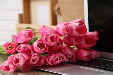 Modern laptop with bouquet of beautiful tulip flowers, closeupの写真素材
