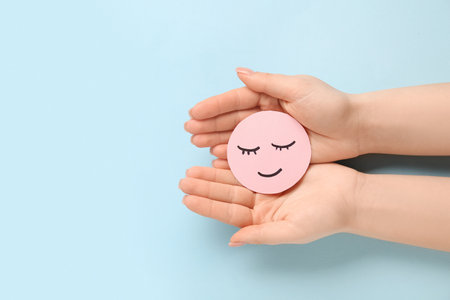 Female hands with paper smile on blue background. World Health Dayの写真素材