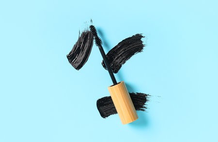 Black mascara brush in wooden tube with samples on blue backgroundの写真素材