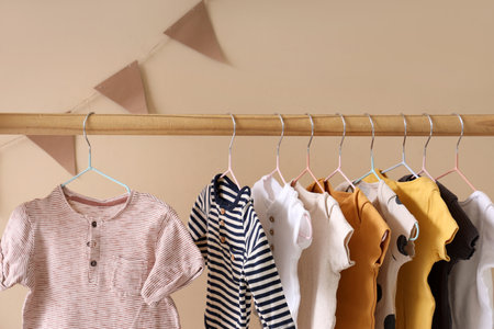 Rack with baby clothes near beige wall in room, closeupの写真素材