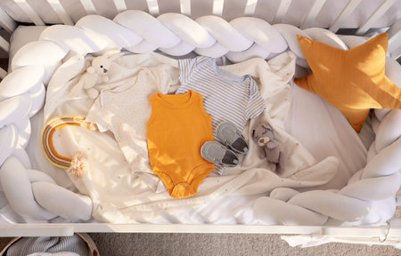 Crib with baby clothes and toys in bedroom, top viewの写真素材