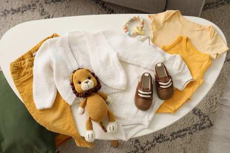 Baby clothes with boots and toys on table in room, top viewの写真素材