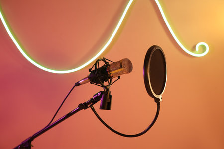 Professional microphone and glowing neon lamp in recording studioの写真素材