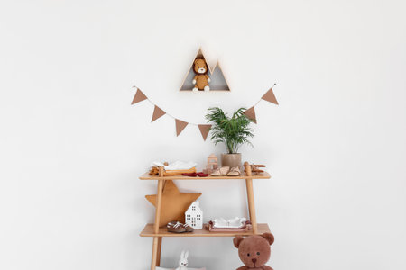 Shelf unit with baby clothes and toys near light wall in nurseryの写真素材