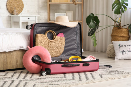 Unpacked suitcase with clothes and travel accessories in hotel roomの写真素材