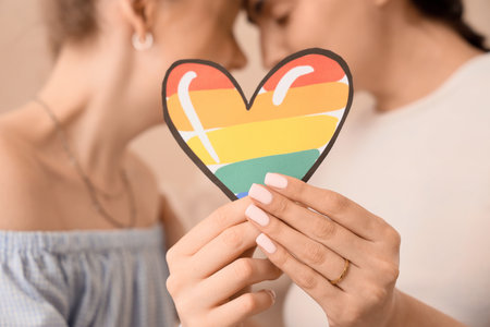 Young pregnant lesbian couple with LGBT heart at home, closeupの写真素材