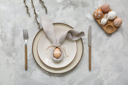 Beautiful table setting with Easter eggs and pussy willow branches on gray background