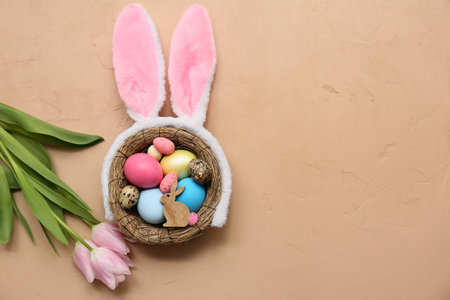 Nest with Easter eggs, bunny ears and beautiful tulip flowers on brown backgroundの写真素材
