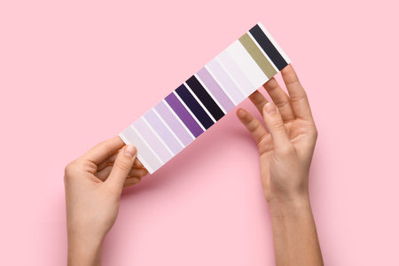 Female hands with violet palette swatches on pink background. Top viewの写真素材