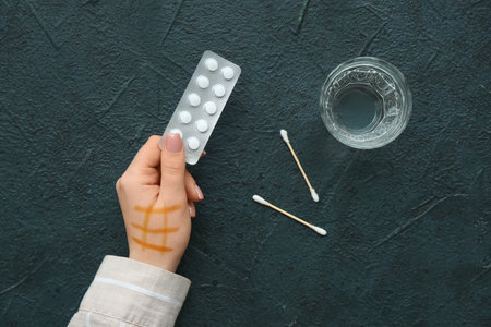 Female hand with iodine mesh, blister of pills and glass of water on black background. Top viewの写真素材