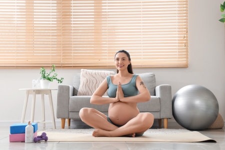 Sporty pregnant woman meditating at homeの写真素材