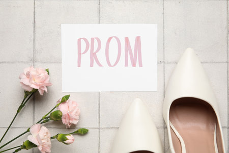 Paper with word PROM, high heels and carnation flowers on white tile backgroundの写真素材