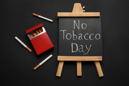 Chalkboard with text NO TOBACCO DAY and cigarettes on black backgroundの写真素材