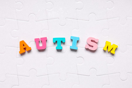 Word AUTISM made of colorful letters on white puzzle pieces