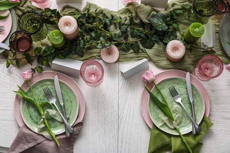 Elegant table setting with beautiful tulip flowers, green leaves and candles in restaurant, top viewの写真素材