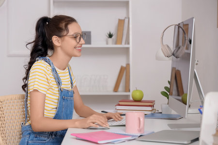 Teenage girl with computer working online at homeの写真素材