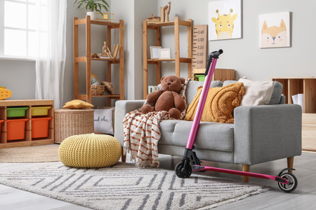 Interior of children's room with electric scooter, shelving units and toys on gray sofaの写真素材