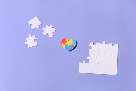 Colorful puzzle pieces in shape of heart on lilac background. Autistic disorder conceptの写真素材