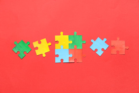 Colorful paper puzzle pieces on red background. Autistic disorder conceptの写真素材