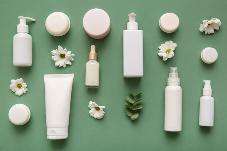 Different cosmetics and beautiful flowers on green backgroundの写真素材