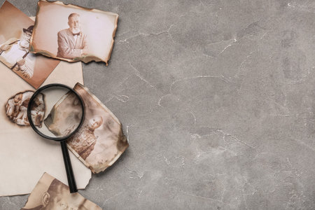 Old photos of relatives with magnifier on grunge background with space for text. Concept of family...