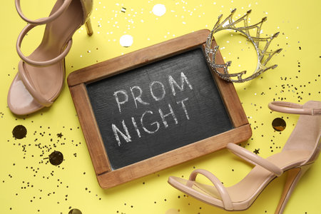 Chalkboard with text PROM NIGHT, high heels, tiara and confetti on yellow backgroundの写真素材