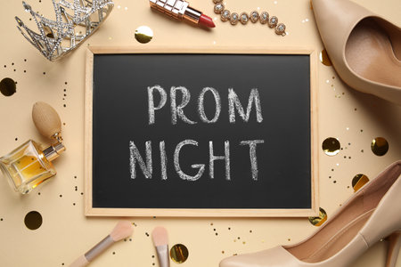 Chalkboard with text PROM NIGHT, high heels, tiara, makeup products and jewelery on beige backgroundの写真素材