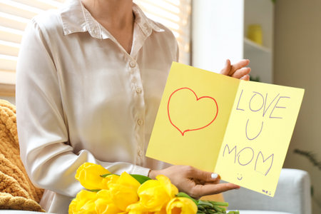 Woman with card for Mother's Day and tulips at home, closeupの写真素材