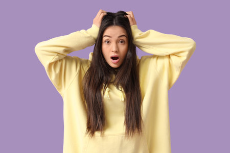 Shocked young woman on lilac background