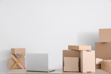 Many different parcels and laptop on table near white wall in roomの写真素材