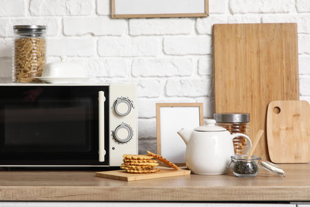Teapot with waffles near microwave oven on table in kitchenの写真素材