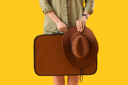 Young woman with suitcase on yellow background, closeup. Travel conceptの写真素材