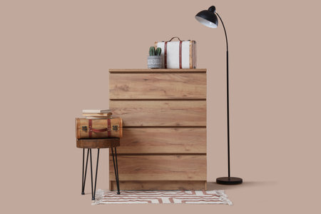 Stylish chest of drawers with cactus and vintage suitcases on beige backgroundの写真素材
