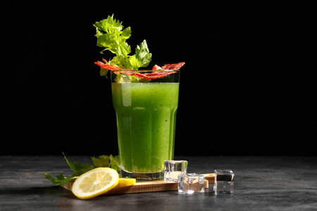 Glass of green bloody mary cocktail with bacon, celery and lemon on black backgroundの写真素材