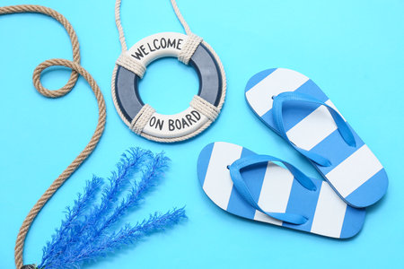 Lifebuoy ring with flip flops, rope and coral on blue background. Summer conceptの写真素材