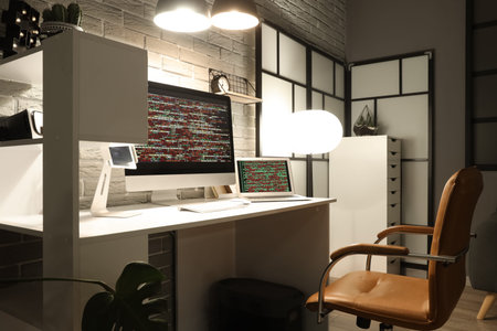Programmer's workplace with gadgets and glowing lamps in office at night