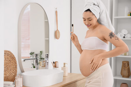 Pregnant woman brushing teeth in bathroomの写真素材