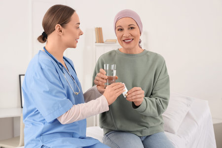 Mature woman after taking chemotherapy pills from nurse in hospital room. Brain cancer concept