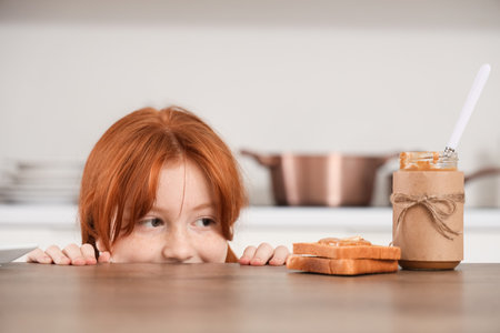 Teenage redhead girl with toasts and nut butter on table in kitchen, closeupの写真素材