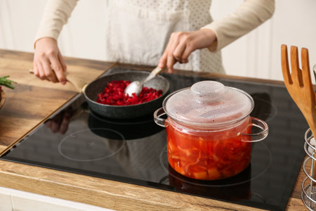 Young woman frying vegetables for delicious borscht in kitchen, closeupの写真素材