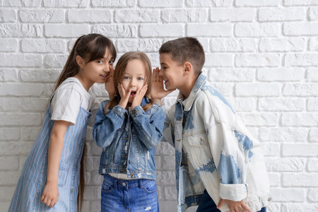 Cute little friends telling secret on white brick backgroundの写真素材