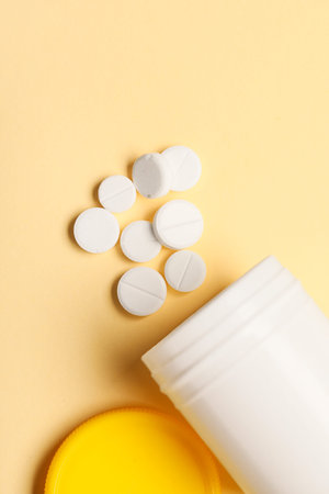 Jar with white pills on yellow background