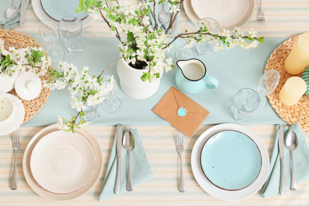 Elegant table setting with plates, envelope and blooming tree branches, top viewの写真素材