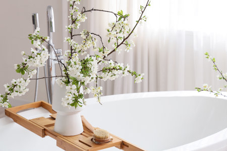 Vase with blossoming branches on bathtub in roomの写真素材